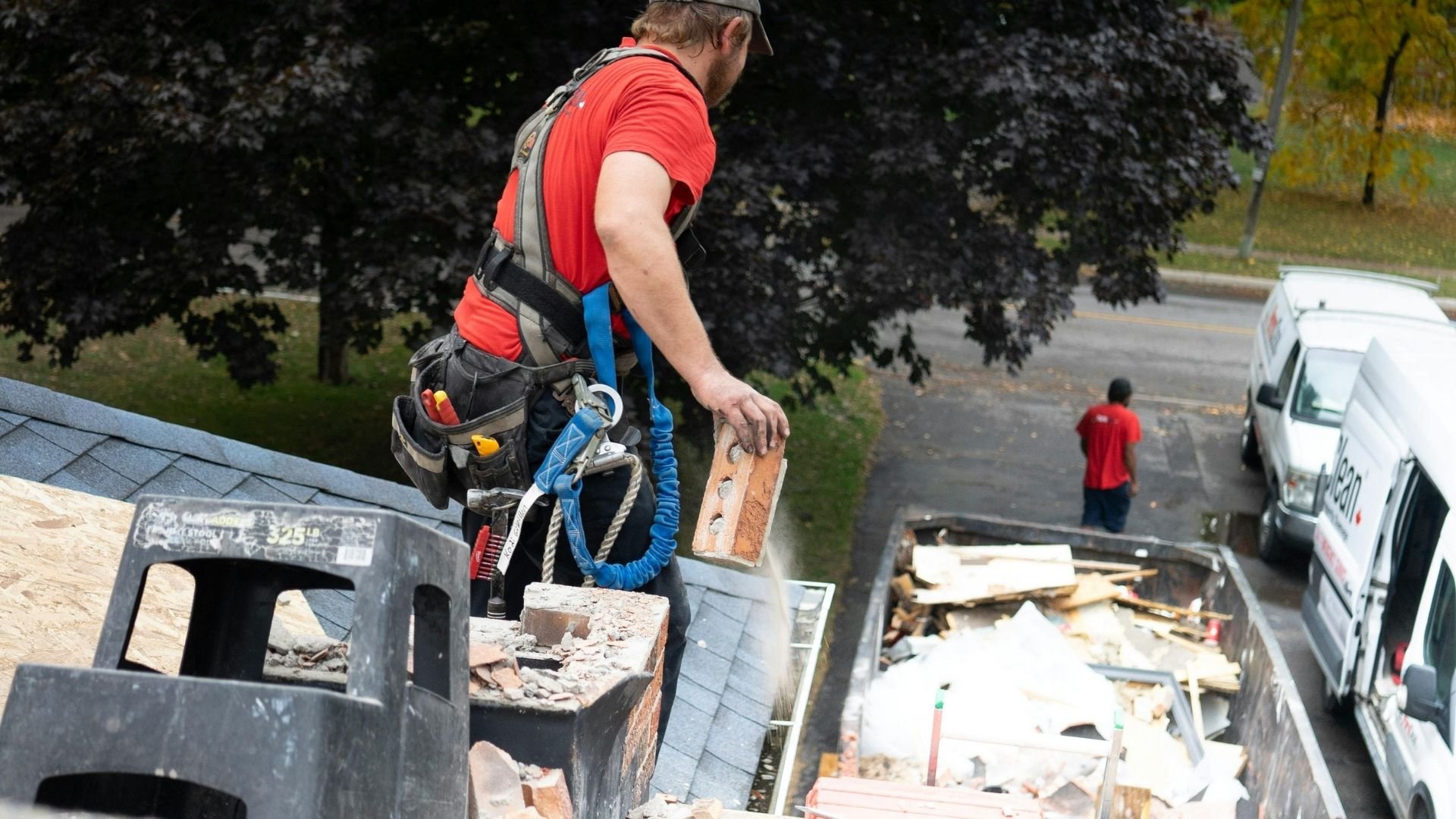 Moving roof debris with safety harness and tools on construction site